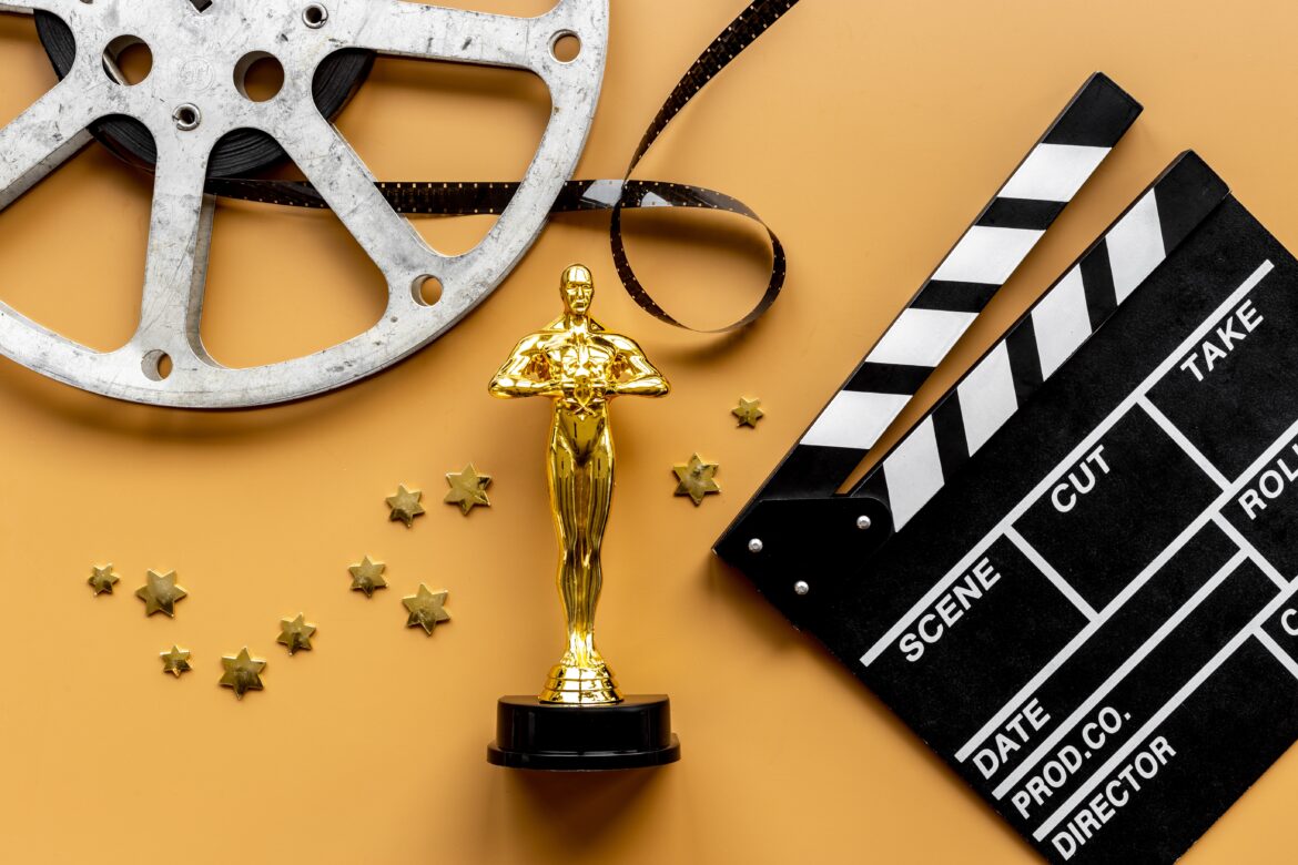 2024 New York Film Critics Circle Award concept with shiny metallic movie award wrapped in celluloid film strip on red carpet with clapper board