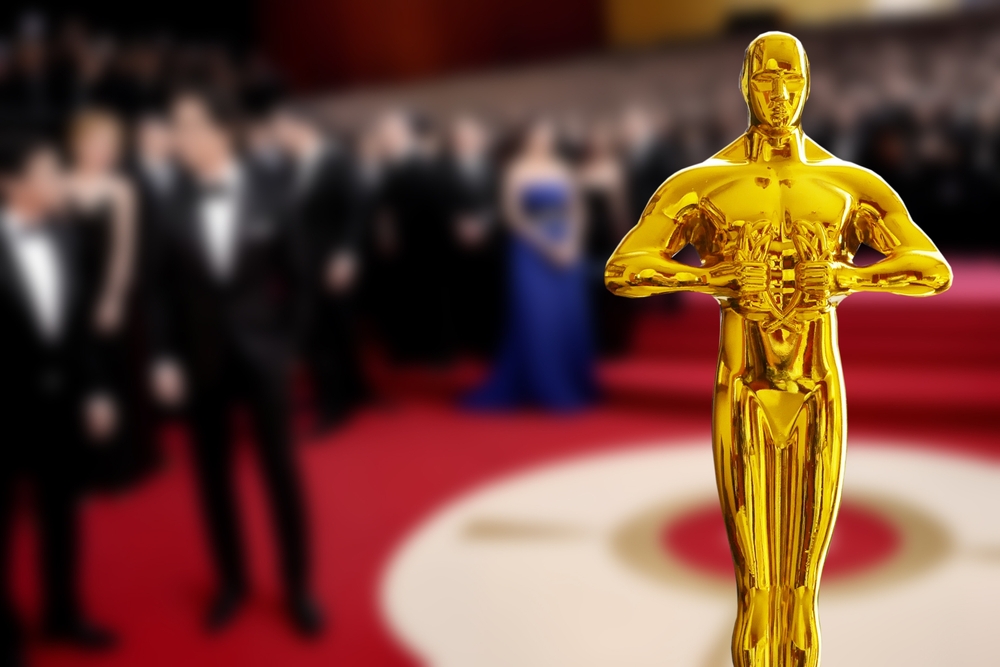 Hollywood Golden Oscar Academy award statue in the hand at the Oscars ceremony background. Success and victory concept.