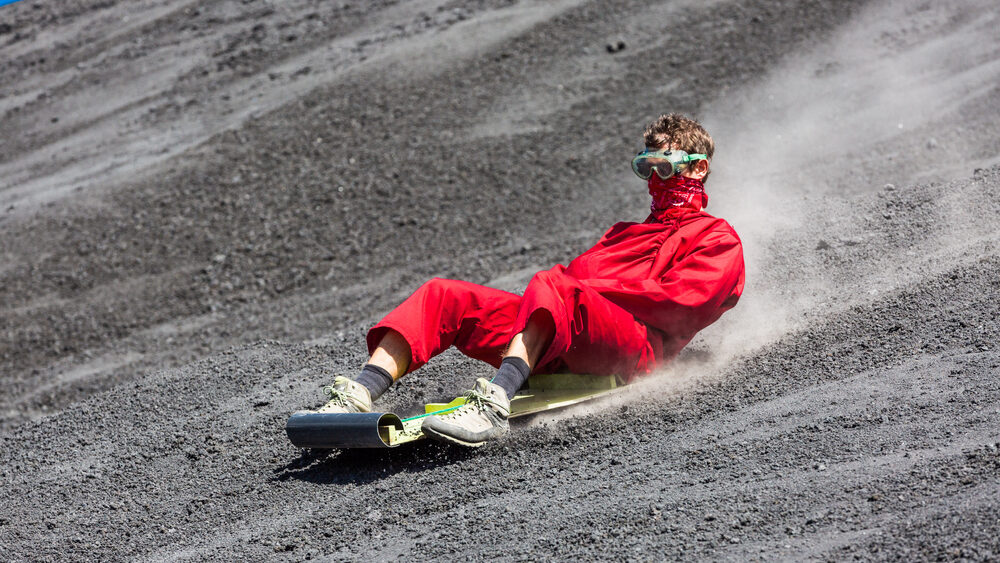 People tourists surf boarding the Cerro Negro Volcano in Nicaragua